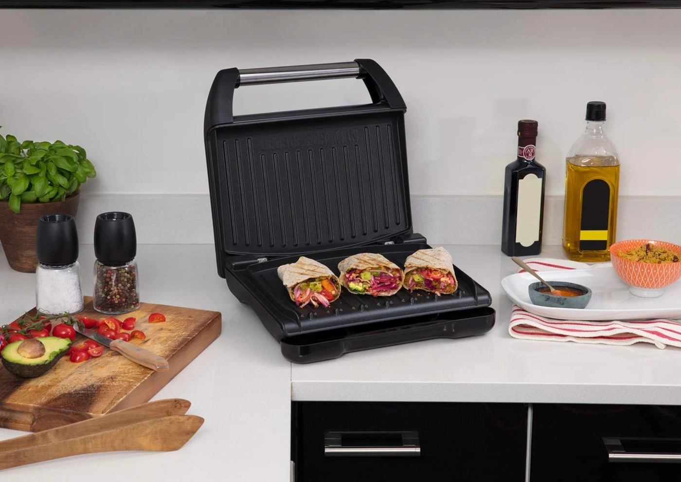 Sandwiches auf einem Grill, daneben Ölflaschen und Zutaten auf der Theke