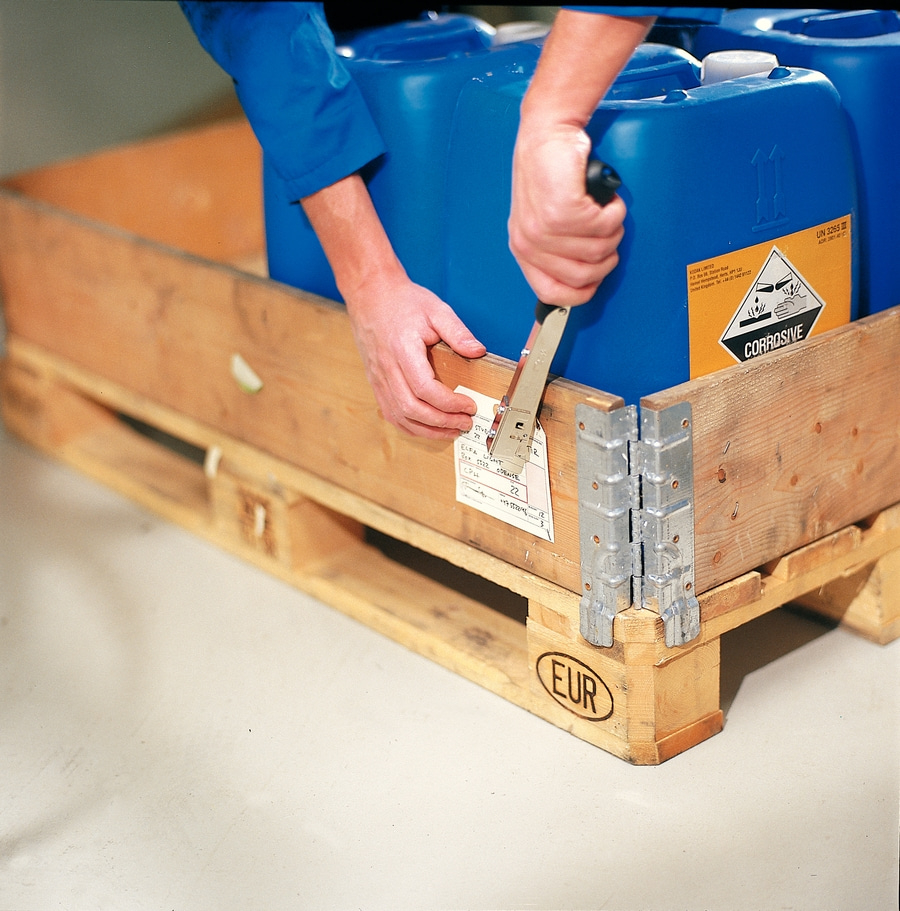 Person sichert blaue Kanister mit einem Tacker auf einer Euro-Palette.