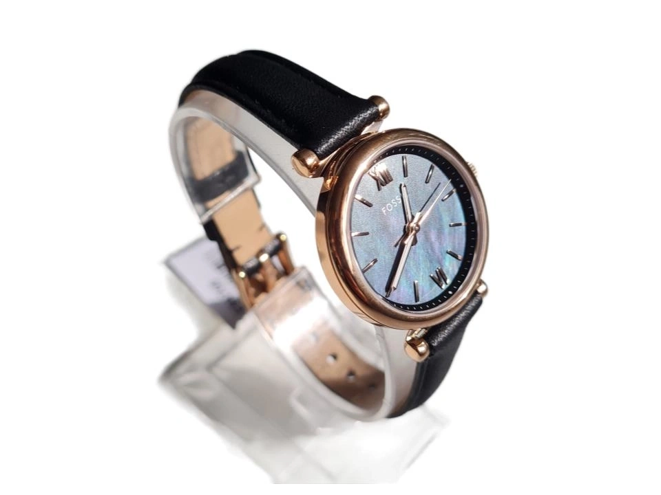 Eine stilvolle Fossil Uhr mit schwarzem Lederarmband und roségoldfarbenem Gehäuse auf einem transparenten Ständer.