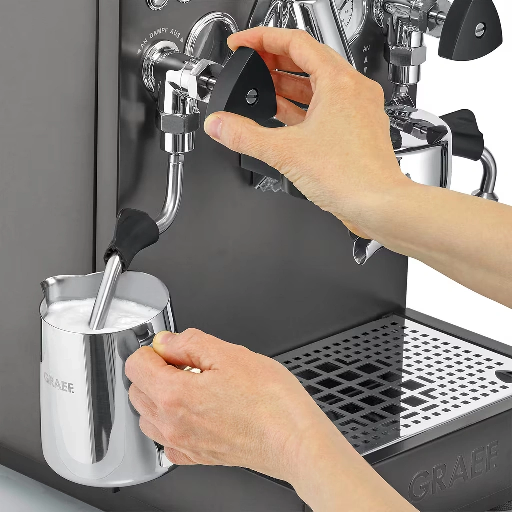 Eine Hand dreht einen Knopf, während die andere einen Milchbehälter hält.