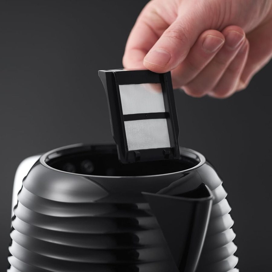Hand hält Filter über schwarzem Wasserkocher, Nahaufnahme, Detailaufnahme, Filter wird eingesetzt