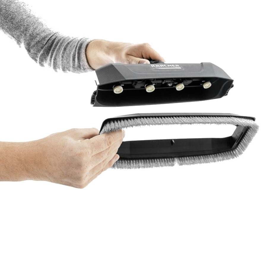 Person hält Staubsaugerbürste. Schwarze Bürste, graue Borsten, weißer Hintergrund.