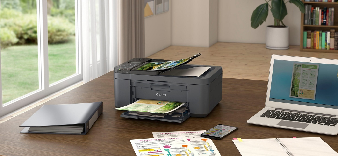 Canon-Drucker auf einem Schreibtisch mit Laptop, Dokumenten und Smartphone.