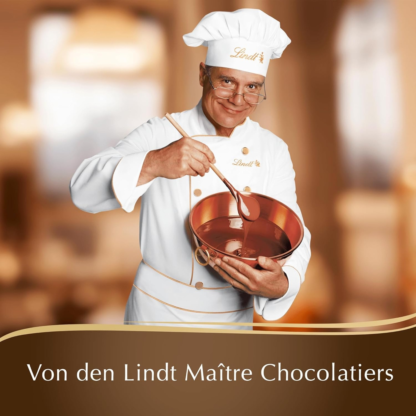 Ein Koch hält einen Kupfertopf mit flüssiger Schokolade und einem Holzlöffel.
