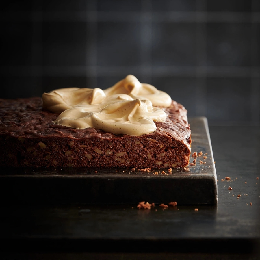Schokoladenkuchen mit Sahne auf einem dunklen Brett, Nahaufnahme, lecker