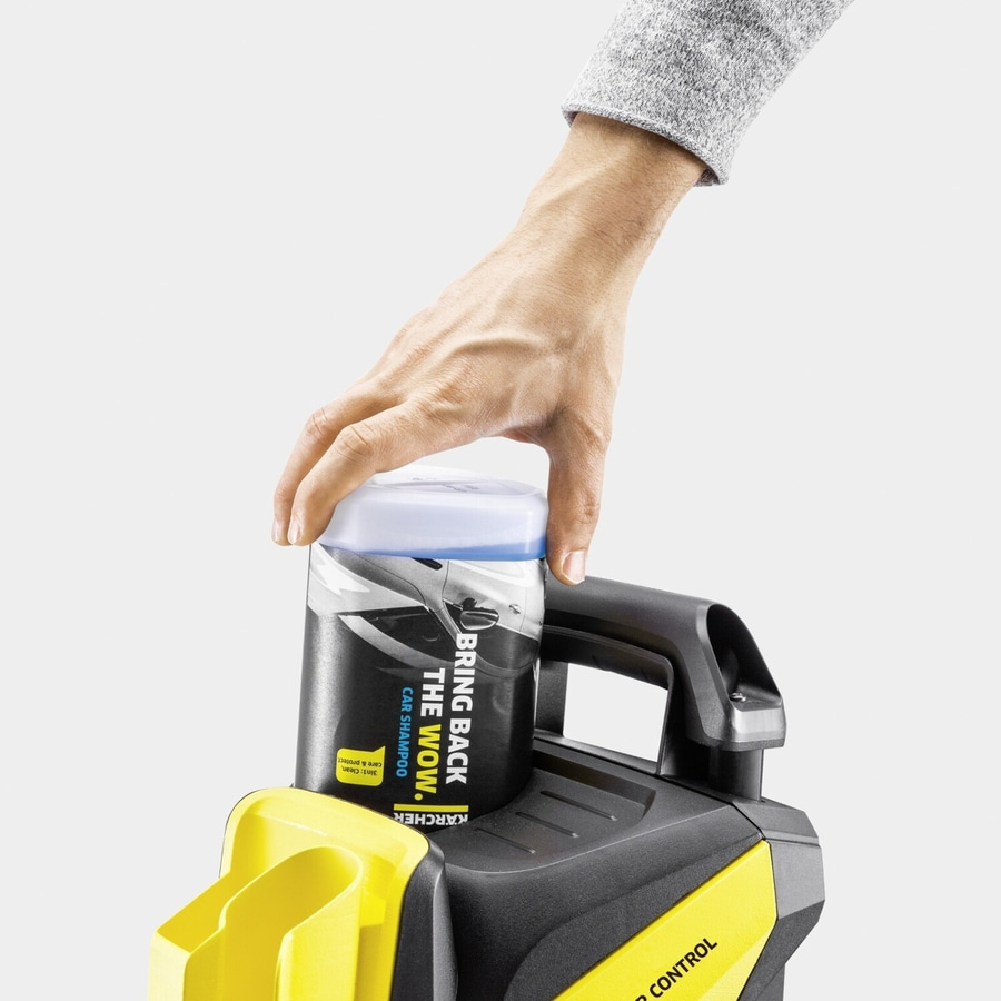 Person hält eine Flasche Autoshampoo auf einem gelb-schwarzen Gerät.