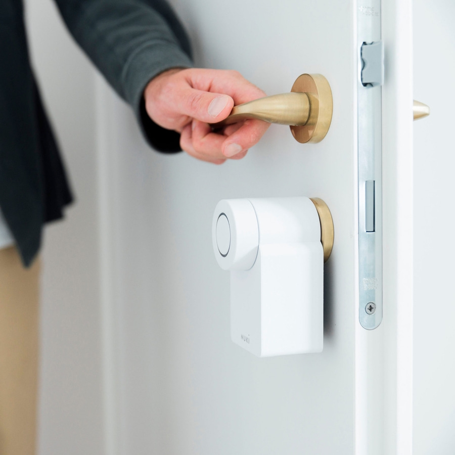 Person öffnet Tür mit goldenem Griff und Smart Lock