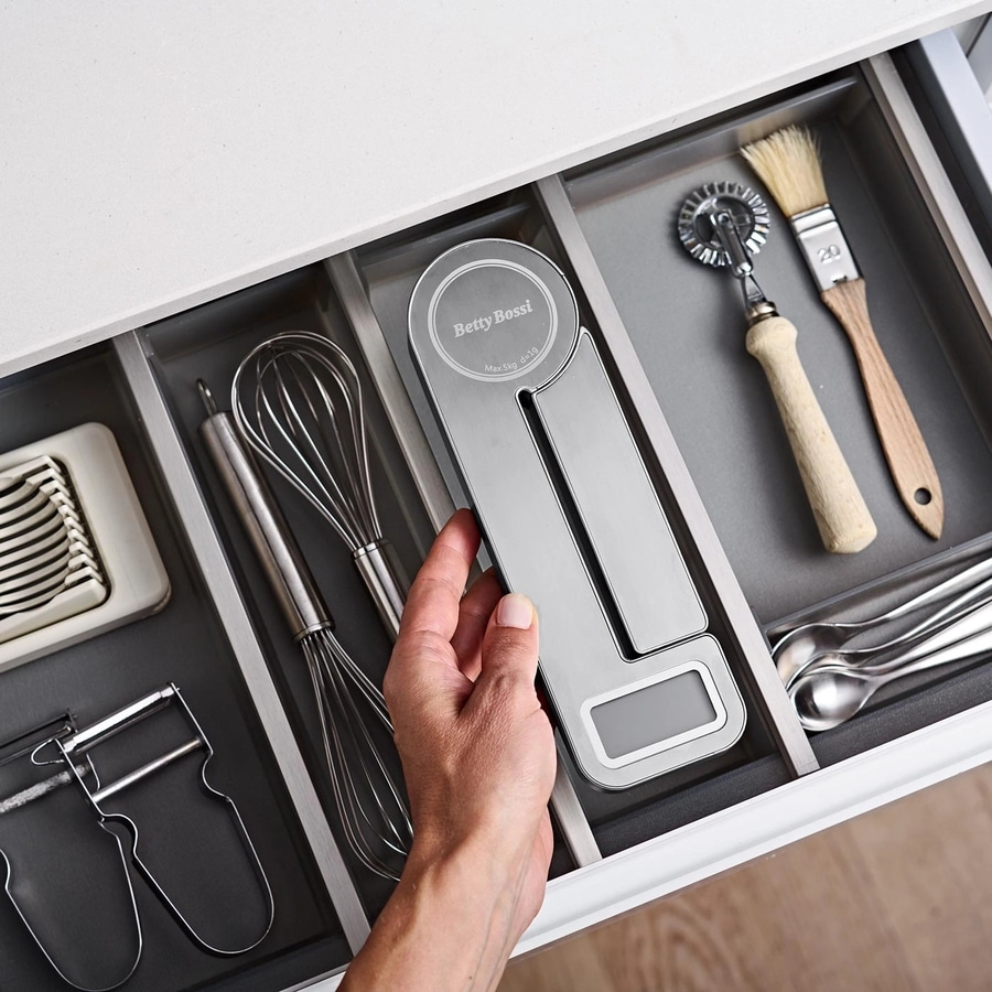 Küchenschublade mit Küchenutensilien, darunter eine Waage und Schneebesen.