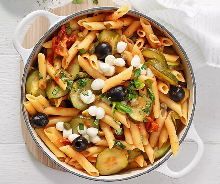 Pasta-Gericht mit Oliven, Mozzarella, Zucchini und Tomaten in einer Schüssel