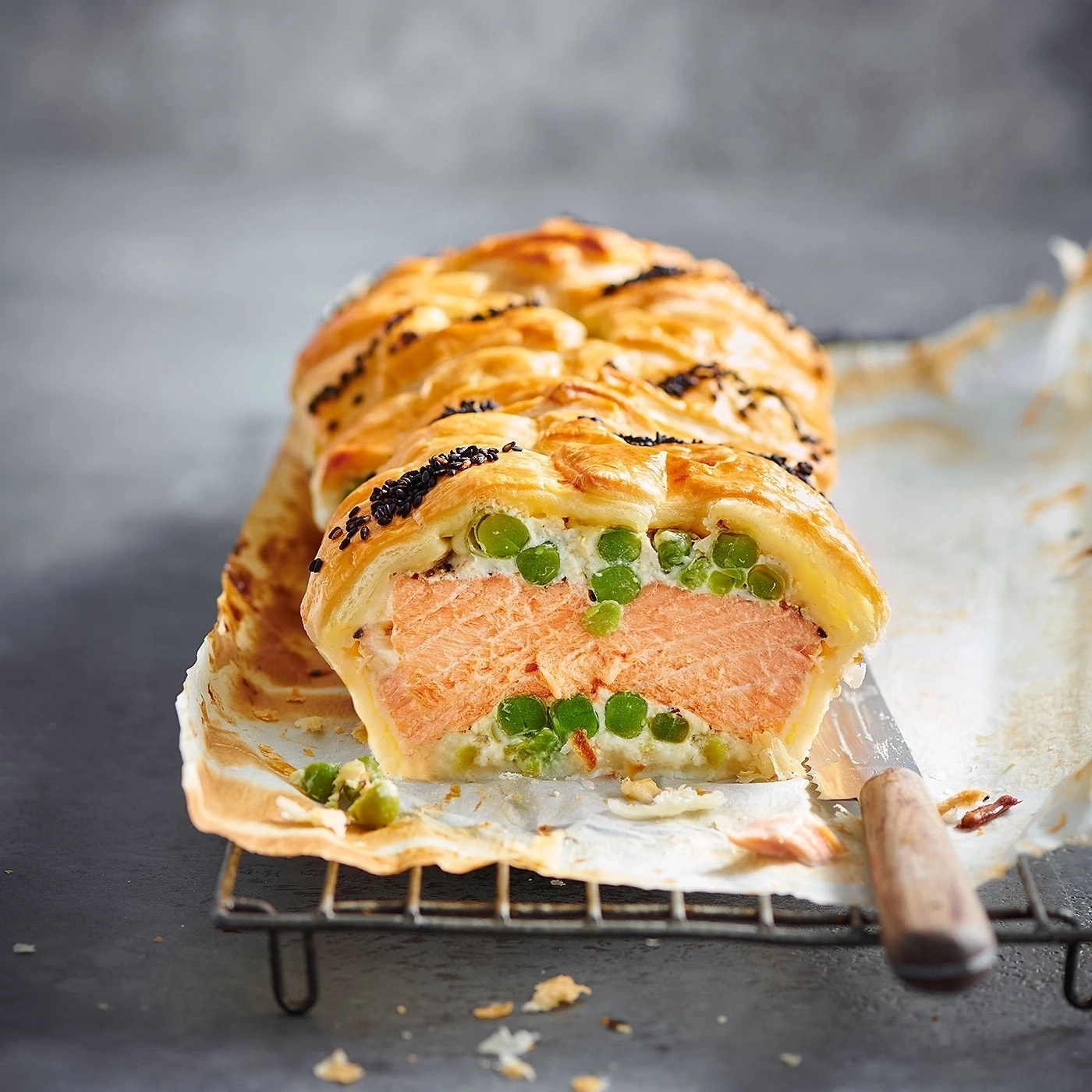 Lachs Wellington mit Erbsen, auf einem Rost, angeschnitten, lecker