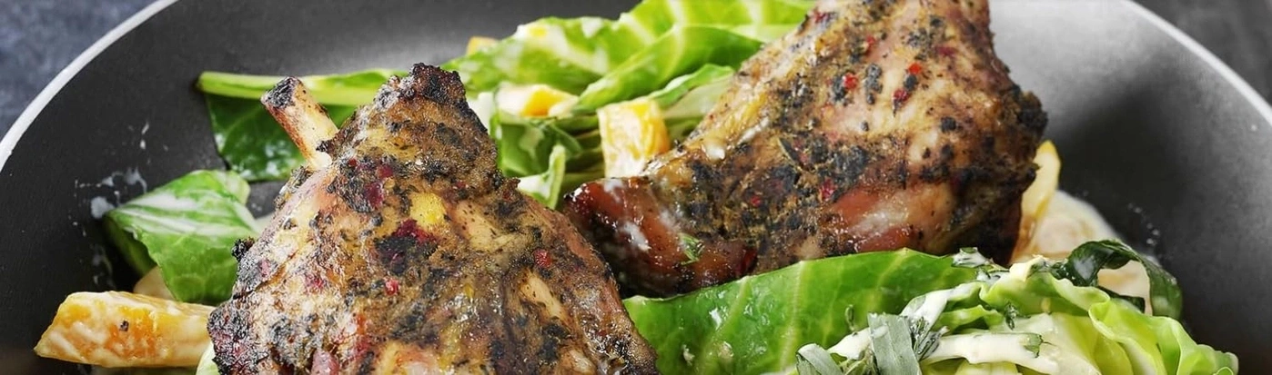 Zwei gegrillte Fleischstücke mit Salat und Sauce auf einem Teller