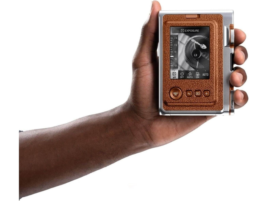 Person hält eine braune Sofortbildkamera mit Display in der Hand.