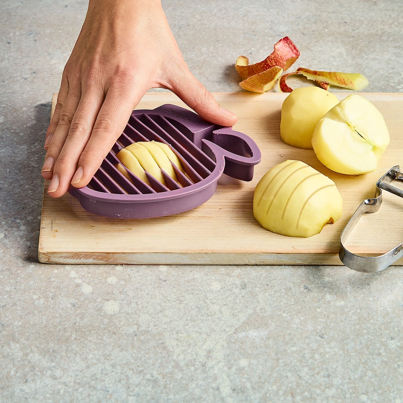 Apfel wird mit einem Apfelschneider geschnitten, auf einem Holzbrett.