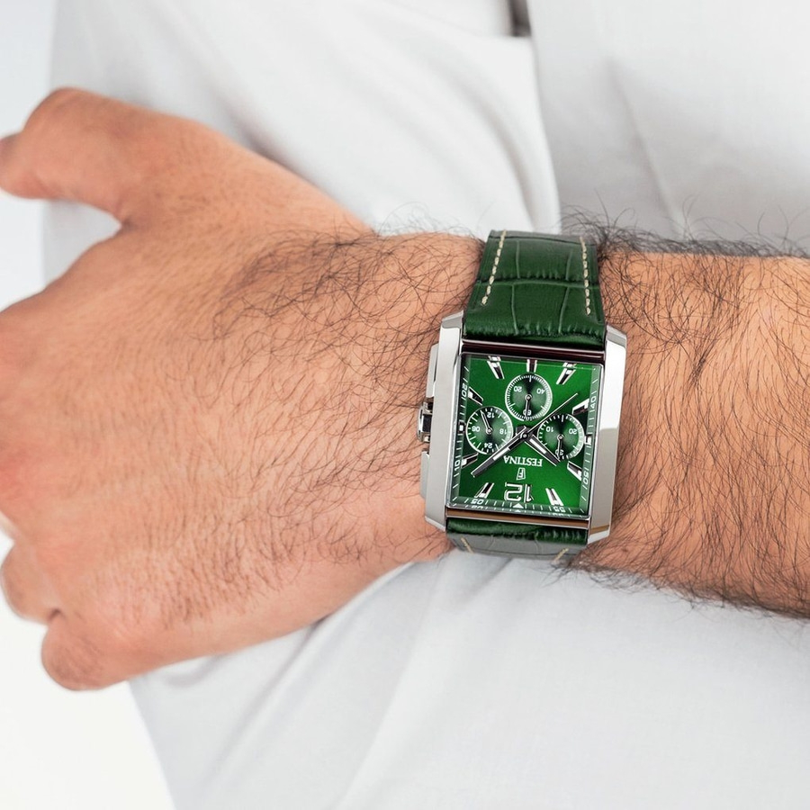 Grüne Herrenuhr mit Lederarmband, am Handgelenk getragen.