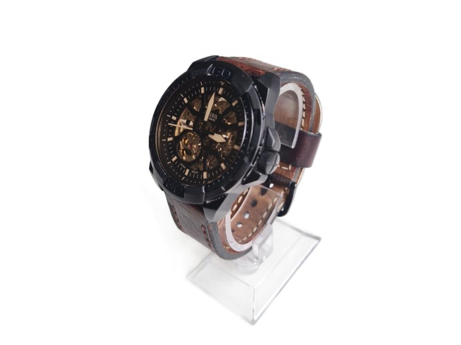 Ein schwarzes Fossil Herrenarmbanduhr mit braunem Lederarmband auf einem Ständer.
