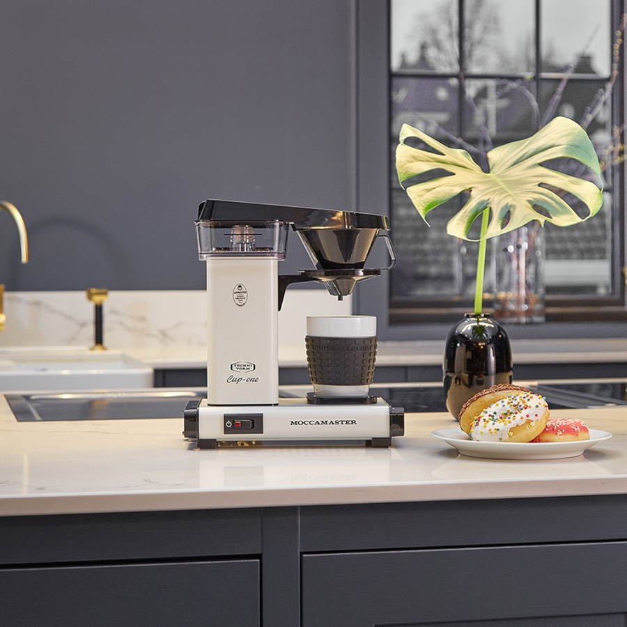 Kaffeemaschine mit Donuts auf einer Theke in einer Küche mit Dekoration.