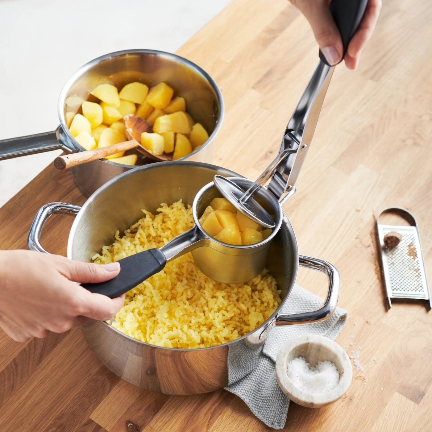 Kartoffeln werden mit einem Kartoffelstampfer zerdrückt, um Püree herzustellen.