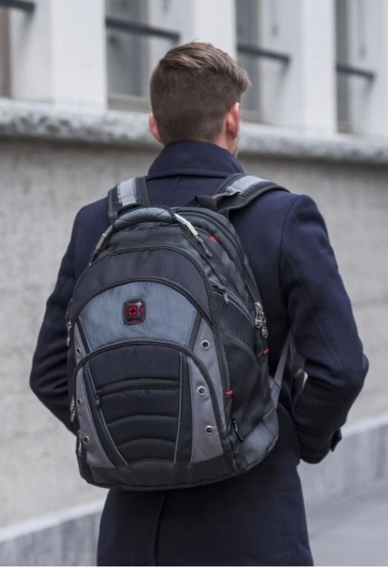 Mann mit Rucksack, der vor einem Gebäude steht, von hinten gesehen