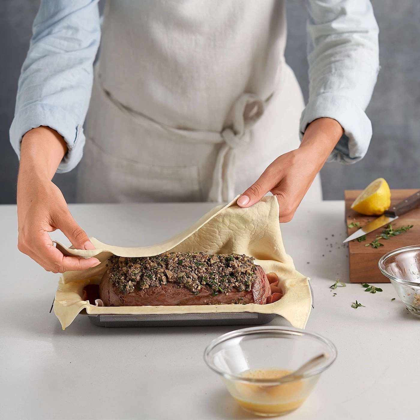 Person bereitet Wellington-Rindfleisch zu, legt Teig über Fleisch, Kochszene, Nahaufnahme.
