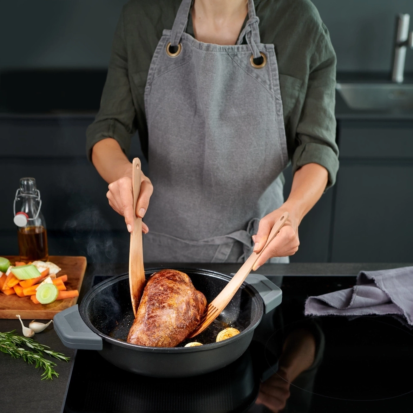 Person kocht Fleisch in einer Pfanne. Kochutensilien, Gemüse, Küche.