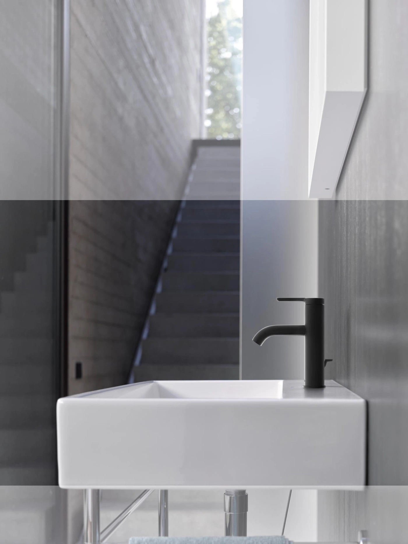 Minimalistisches Badezimmer mit Waschbecken und Treppe im Hintergrund. Schwarze Armatur.
