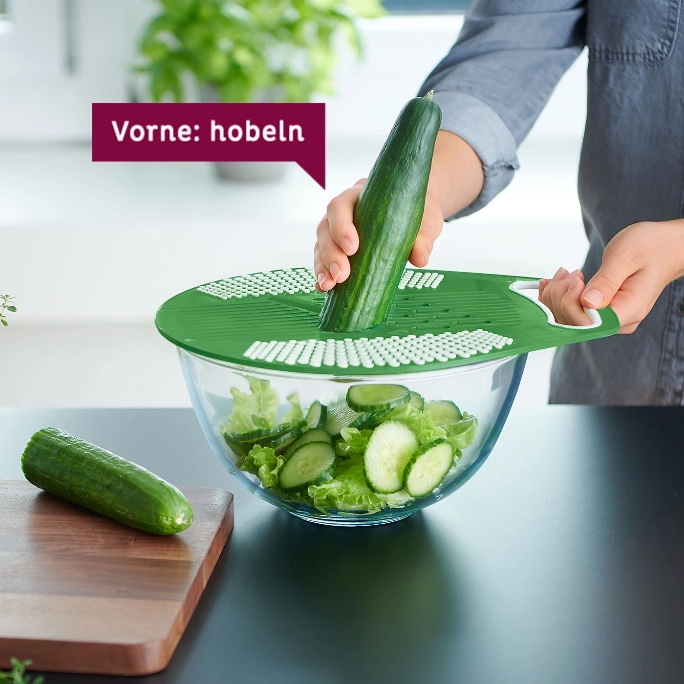 Eine Person hobelt eine Gurke über eine Salatschüssel