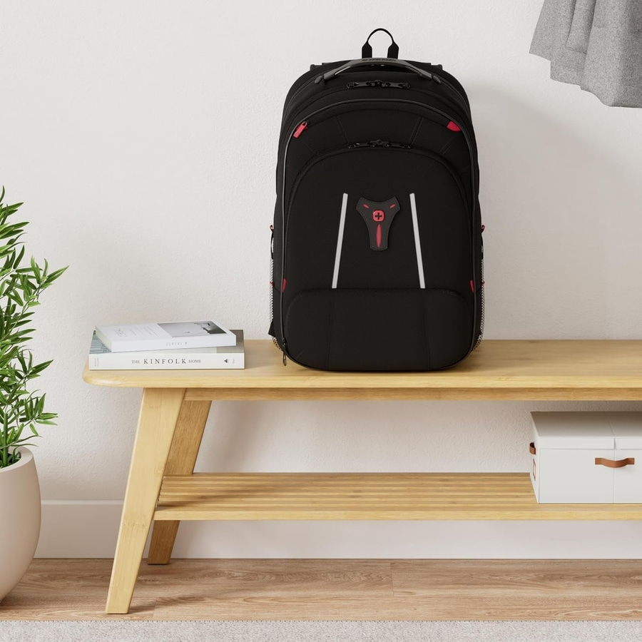 Schwarzer Rucksack auf einer Holzbank mit Büchern und einer Pflanze