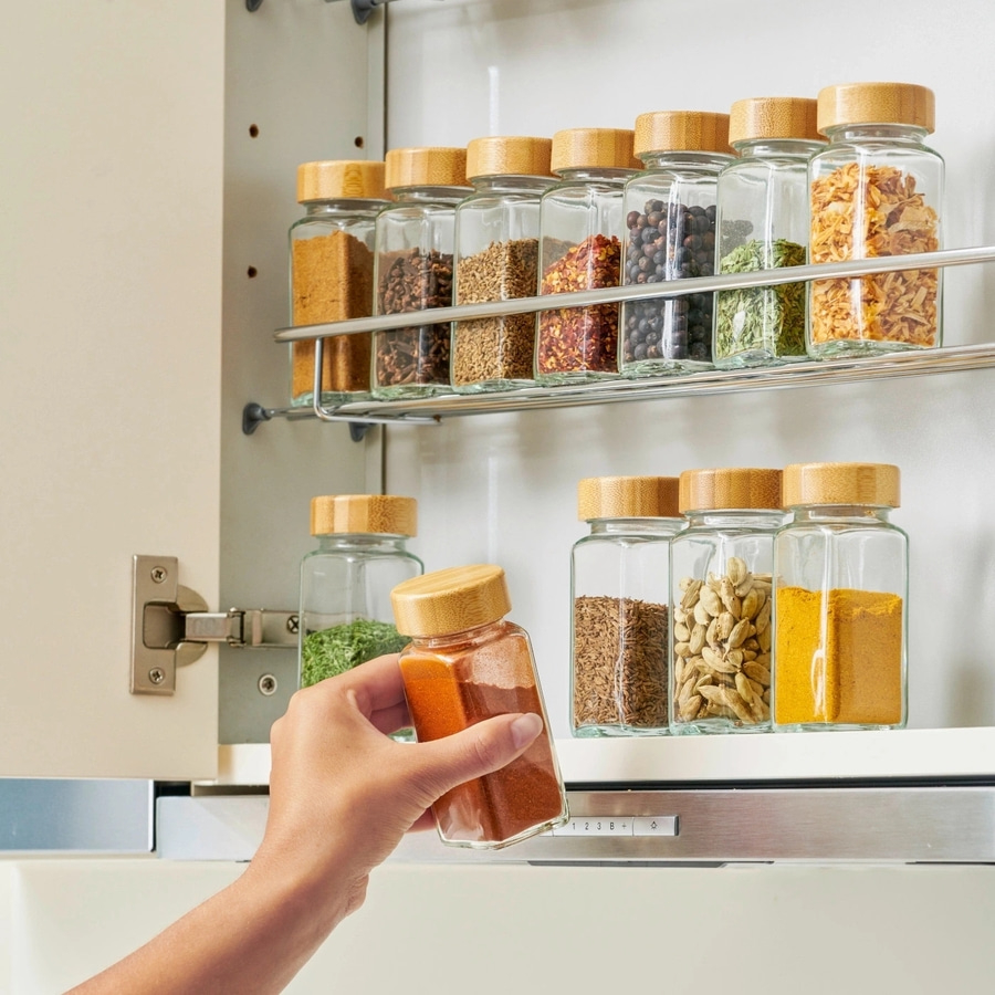 Gewürzregal mit Gläsern, Hand hält Gewürzglas, Küche, Nahaufnahme