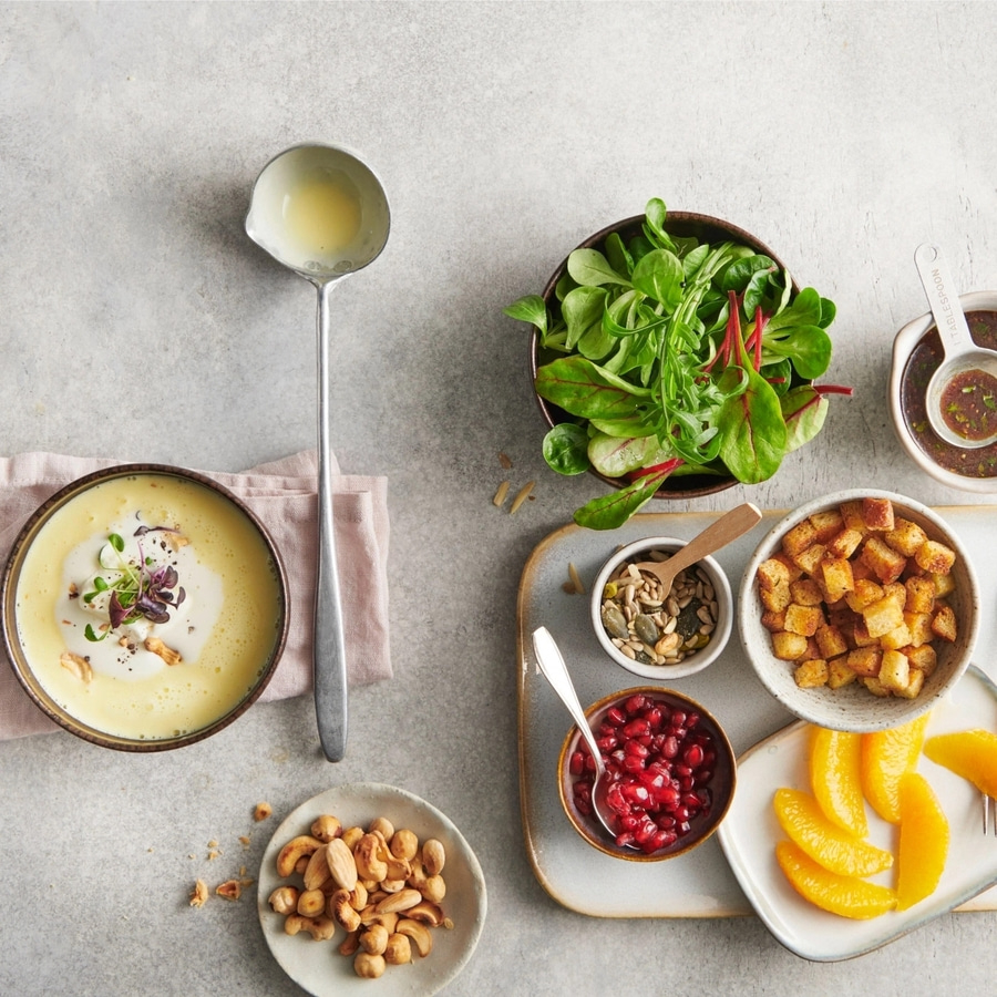 Suppe mit Beilagen: Croutons, Nüsse, Salat, Orangen, Granatapfelkerne, Dressing.