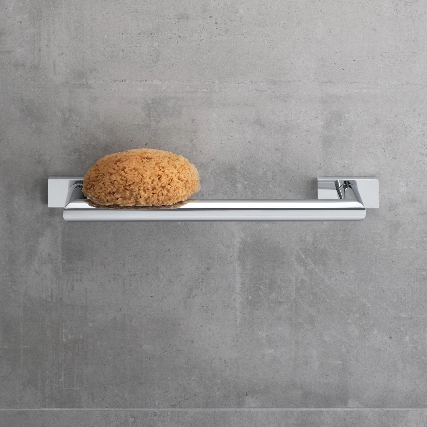 Schwamm auf Chrom-Handtuchhalter vor grauer Wand. Badezimmer-Dekoration.