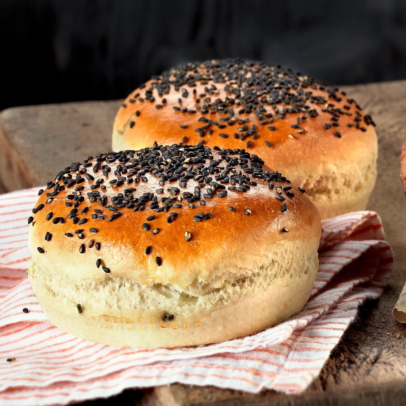Zwei Brötchen mit Sesam auf einem rot-weiß gestreiften Tuch