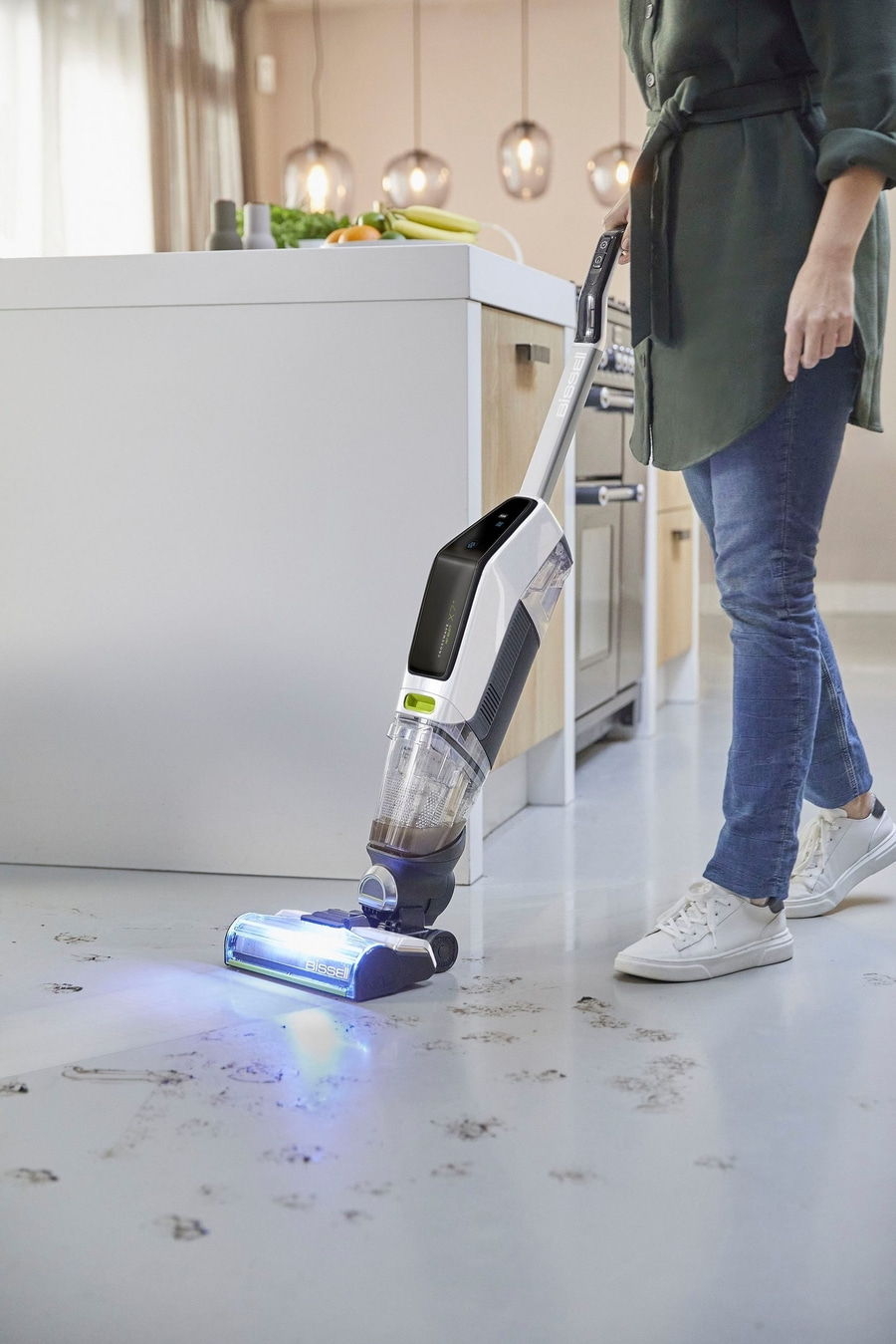 Eine Person reinigt einen schmutzigen Boden mit einem Bissell Staubsauger im Wohnzimmer.