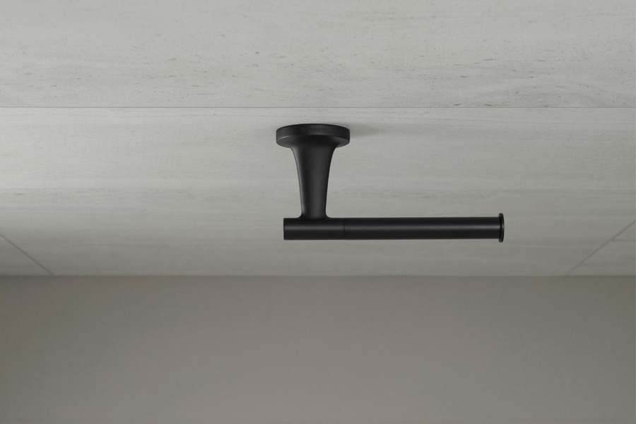 Schwarzer Toilettenpapierhalter an einer grauen Wand. Badezimmer-Dekoration.