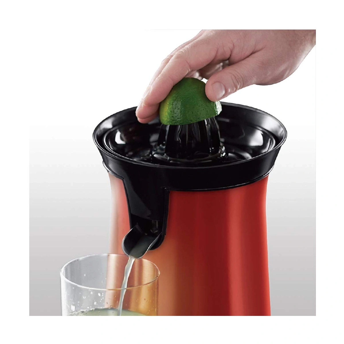 Person presst Limette in eine Saftpresse, Saft fließt in ein Glas.