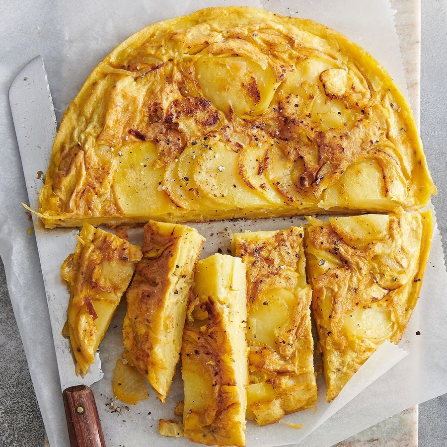 Spanische Tortilla, geschnitten, auf Backpapier, mit Messer, Nahaufnahme
