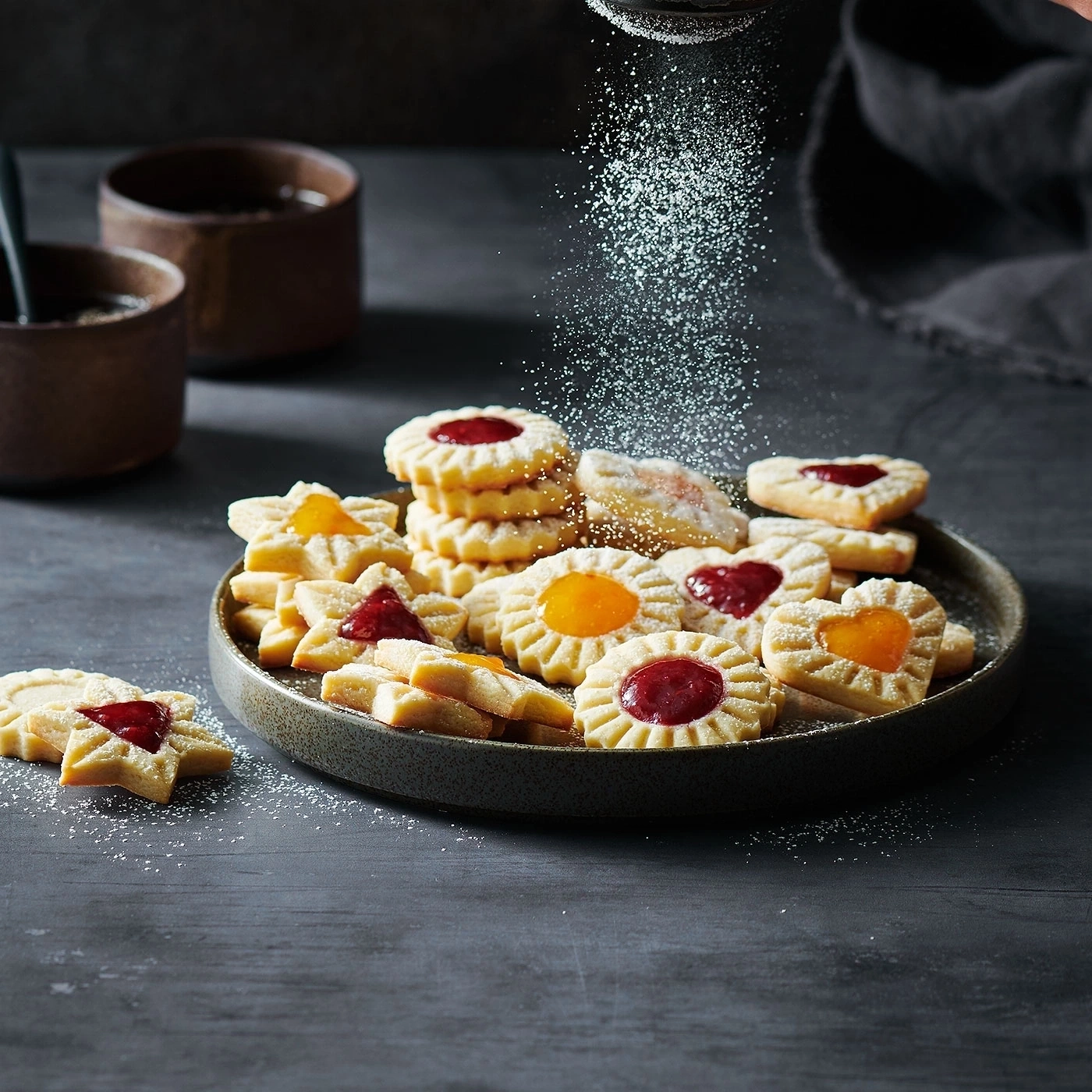 Plätzchen mit Marmelade und Puderzucker bestreut