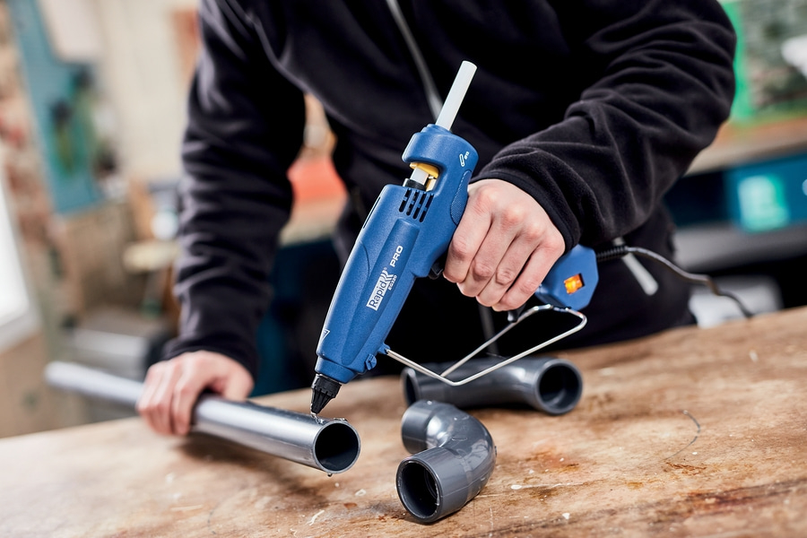 Heißklebepistole klebt an Kunststoffrohr. Werkstatt.