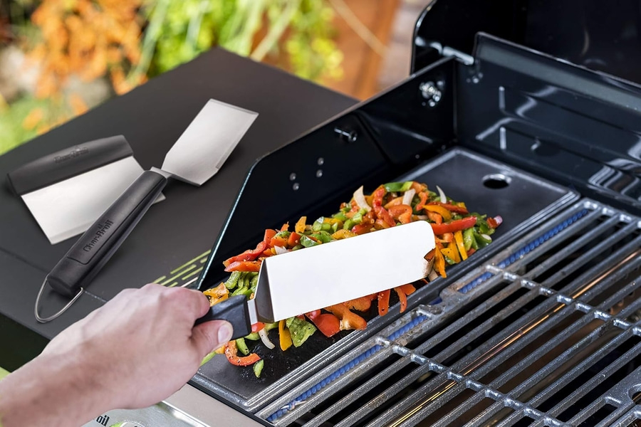Person grillt Gemüse mit einem Spatel auf einem Grill. Nahaufnahme.
