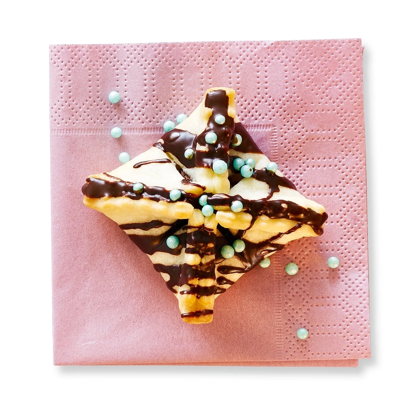 Gebäck mit Schokoladenüberzug und blauen Kügelchen auf rosa Serviette