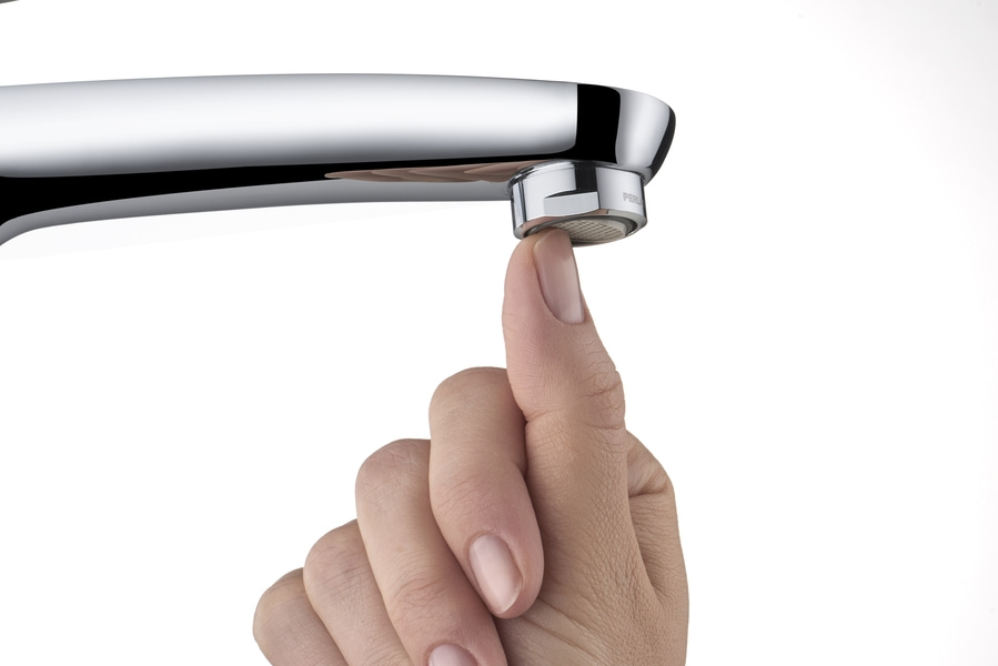 Nahaufnahme einer Hand, die einen Wasserhahn berührt, mit weißem Hintergrund und glänzendem Wasserhahn