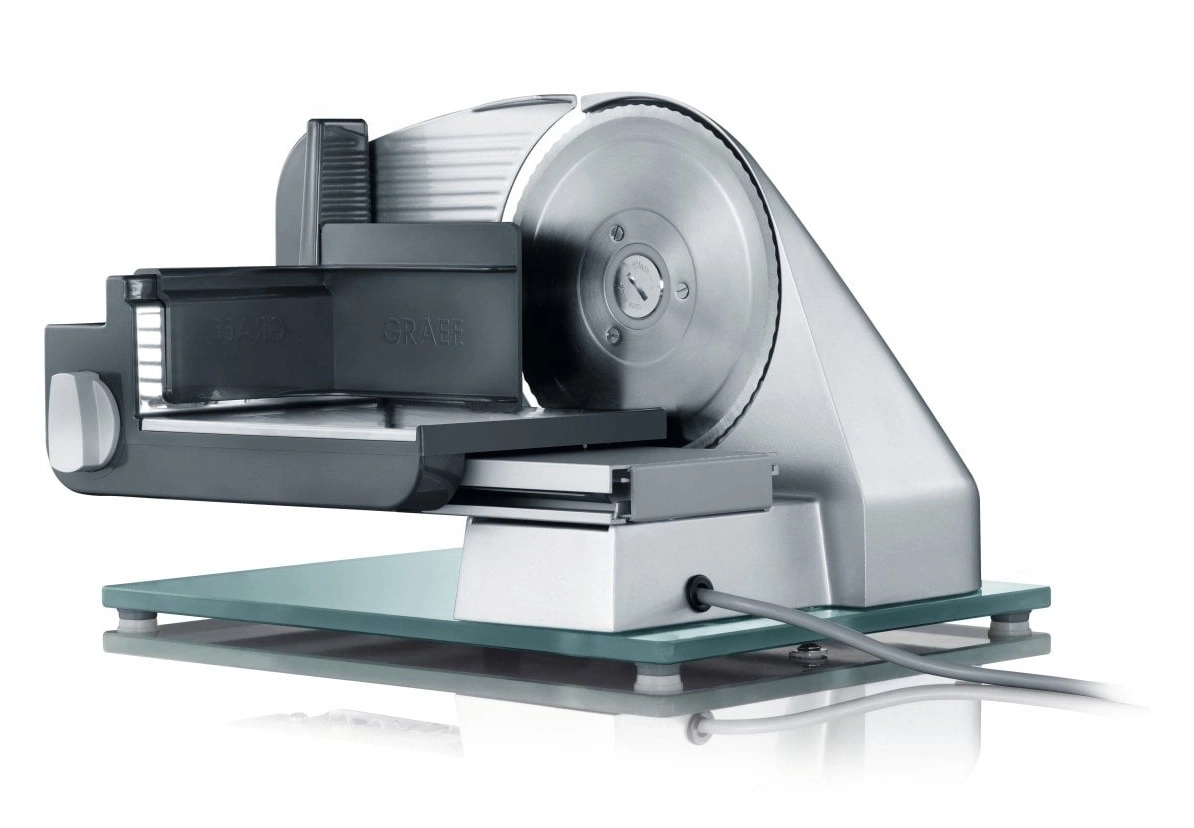 Ein elektrischer Brotschneider mit silbernem Metallgehäuse und Glasplatte.