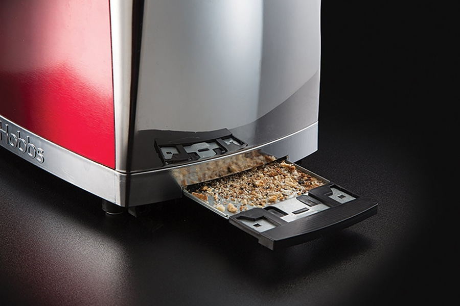 Nahaufnahme eines Toasters mit herausgezogener Krümelschublade, gefüllt mit Brotkrümeln.
