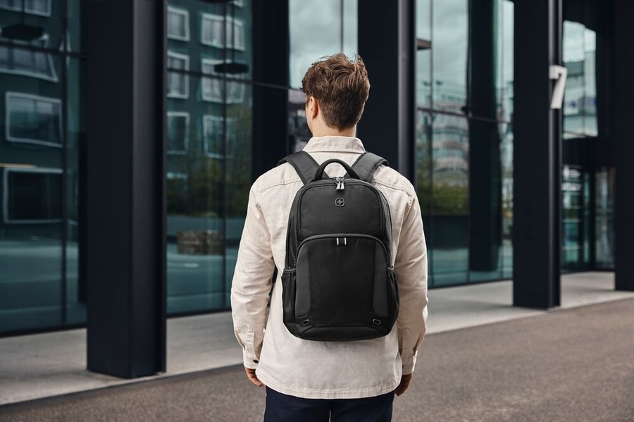 Mann mit schwarzem Rucksack vor einem modernen Gebäude