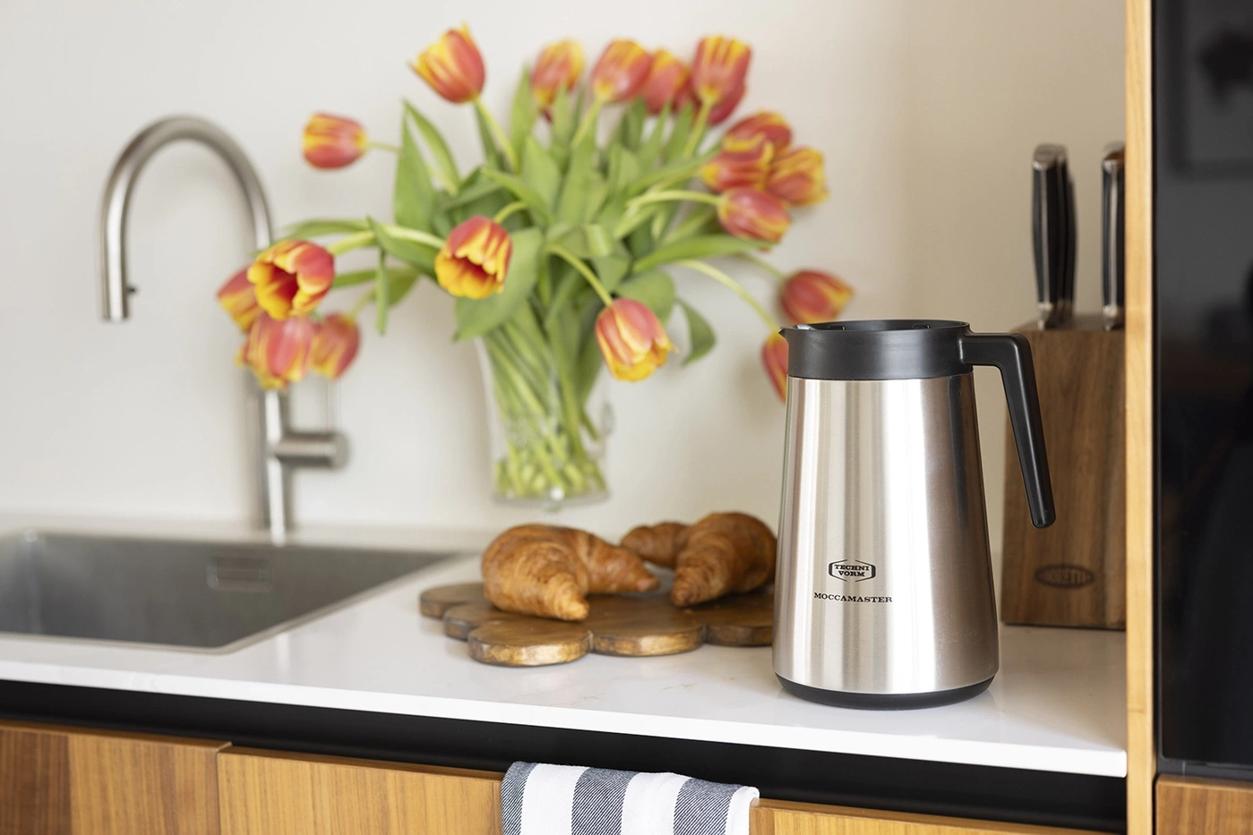 Kaffeekanne, Croissants und Tulpen auf einer Küchenarbeitsplatte