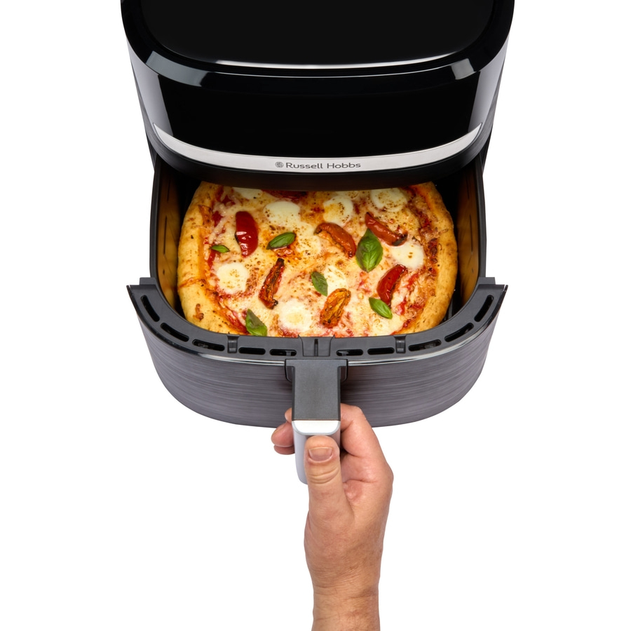 Luftfritteuse mit Pizza, die von einer Hand herausgezogen wird, isoliert auf Weiß