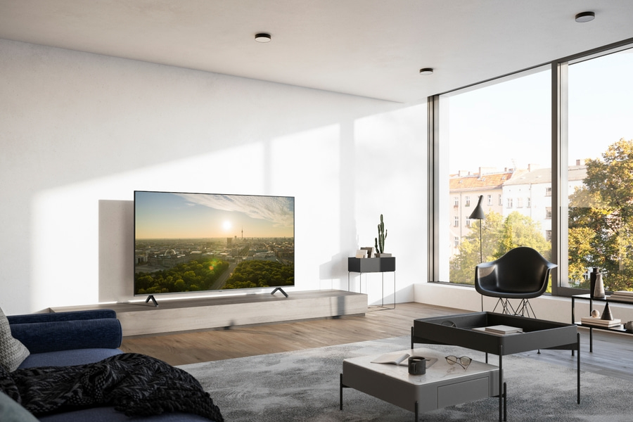 Wohnzimmer mit Fernseher, Fenster, Stuhl, Tisch und Dekoration. Helles, modernes Interieur.