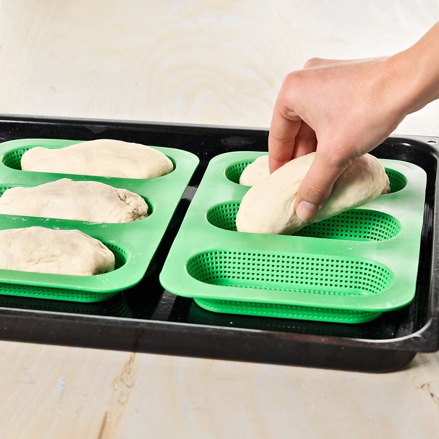 Person legt Teig in grüne Backform. Brotbacken in der Küche. Backutensilien.
