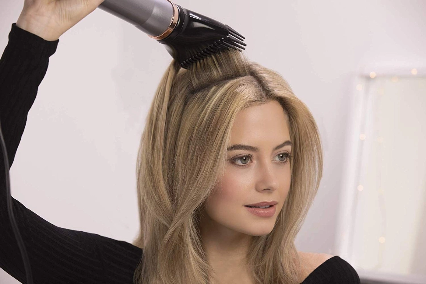 Frau föhnt sich die Haare mit einer Haarbürste. Blondes Haar, Nahaufnahme.