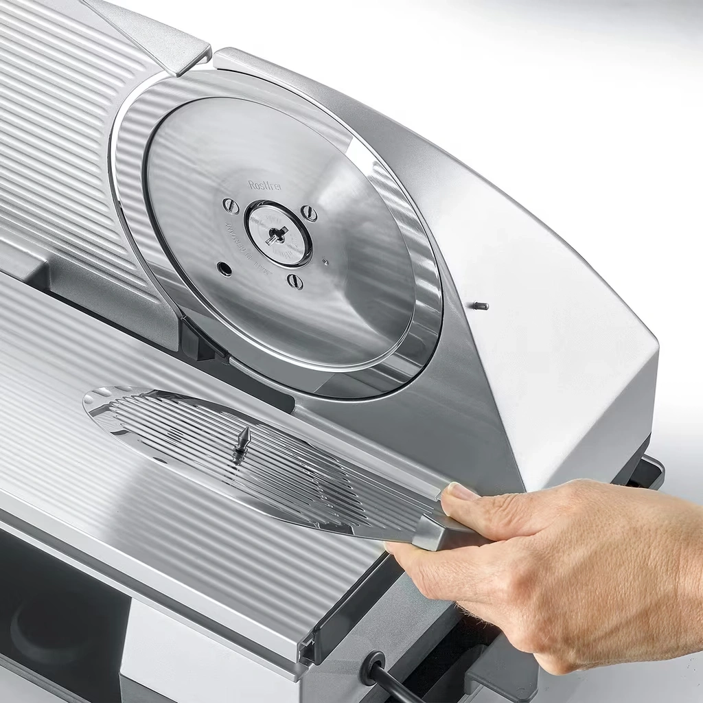 Eine Hand bedient eine elektrische Brotschneidemaschine mit grossem metallischem Messer.