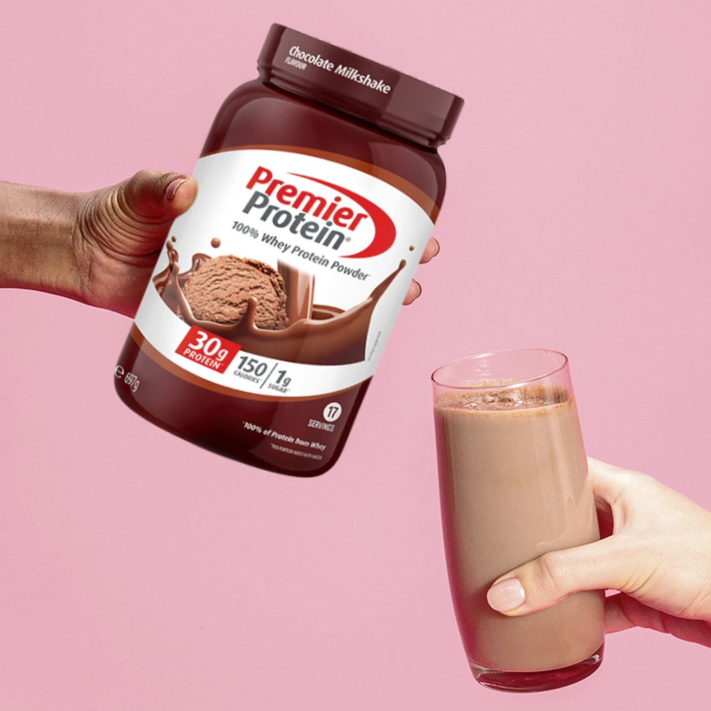 Premier Protein Schokoladen-Milchshake Pulver wird gehalten, dazu ein Glas Milchshake.